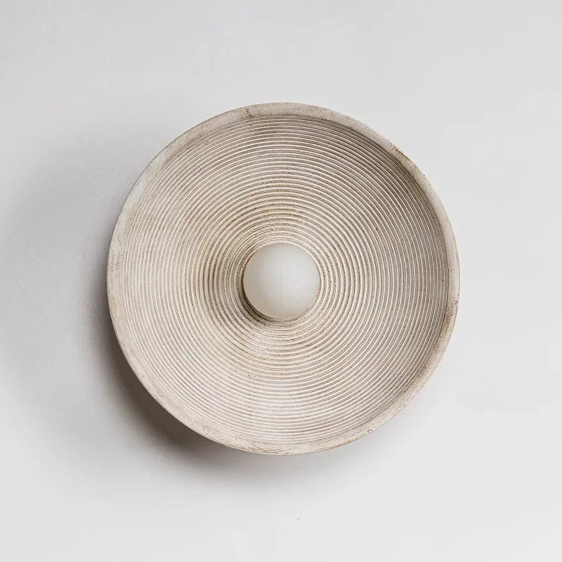 Applique murale ronde en résine texturée de style japonais, avec lignes concentriques et ampoule LED au centre. Idéale pour une atmosphère calme et minimaliste.