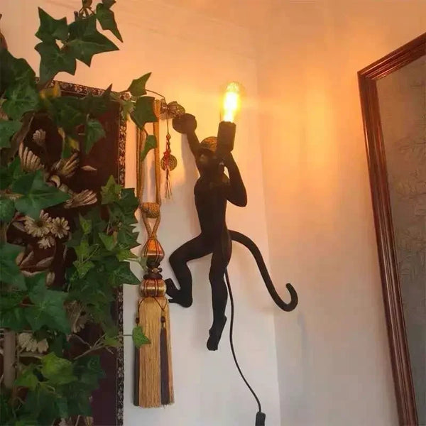Applique murale décorative en forme de singe sculpté tenant une ampoule, fixée verticalement pour un effet visuel saisissant. Idéale pour un intérieur au design audacieux.