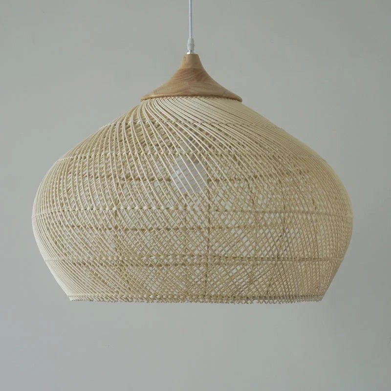 Suspension bombée en rotin tressé ajouré, suspendue par un câble discret et surmontée d’un élément en bois clair. La lumière filtre à travers le motif graphique pour créer des jeux d’ombres doux, apportant une ambiance naturelle et élégante à la pièce.