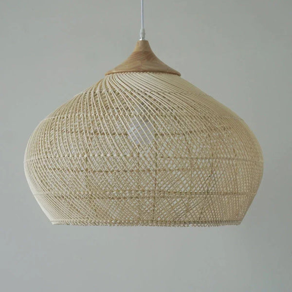 Suspension bombée en rotin tressé ajouré, suspendue par un câble discret et surmontée d’un élément en bois clair. La lumière filtre à travers le motif graphique pour créer des jeux d’ombres doux, apportant une ambiance naturelle et élégante à la pièce.